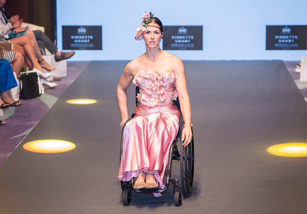 Samanta Bullock wearing a beautiful pink dress while wheeling her wheelchair on a fashion catwalk