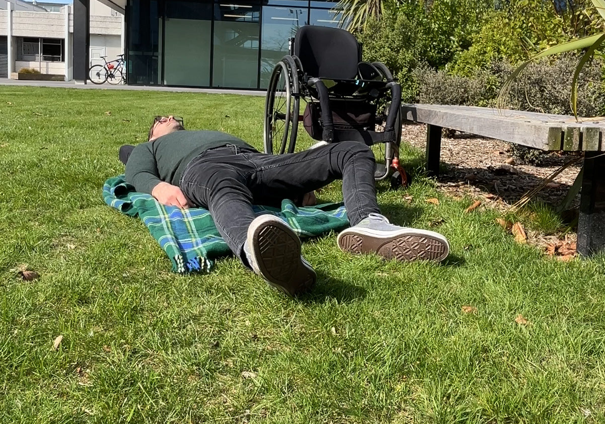 a man lying on the grass after doing a wheelchair to floor transfer.
