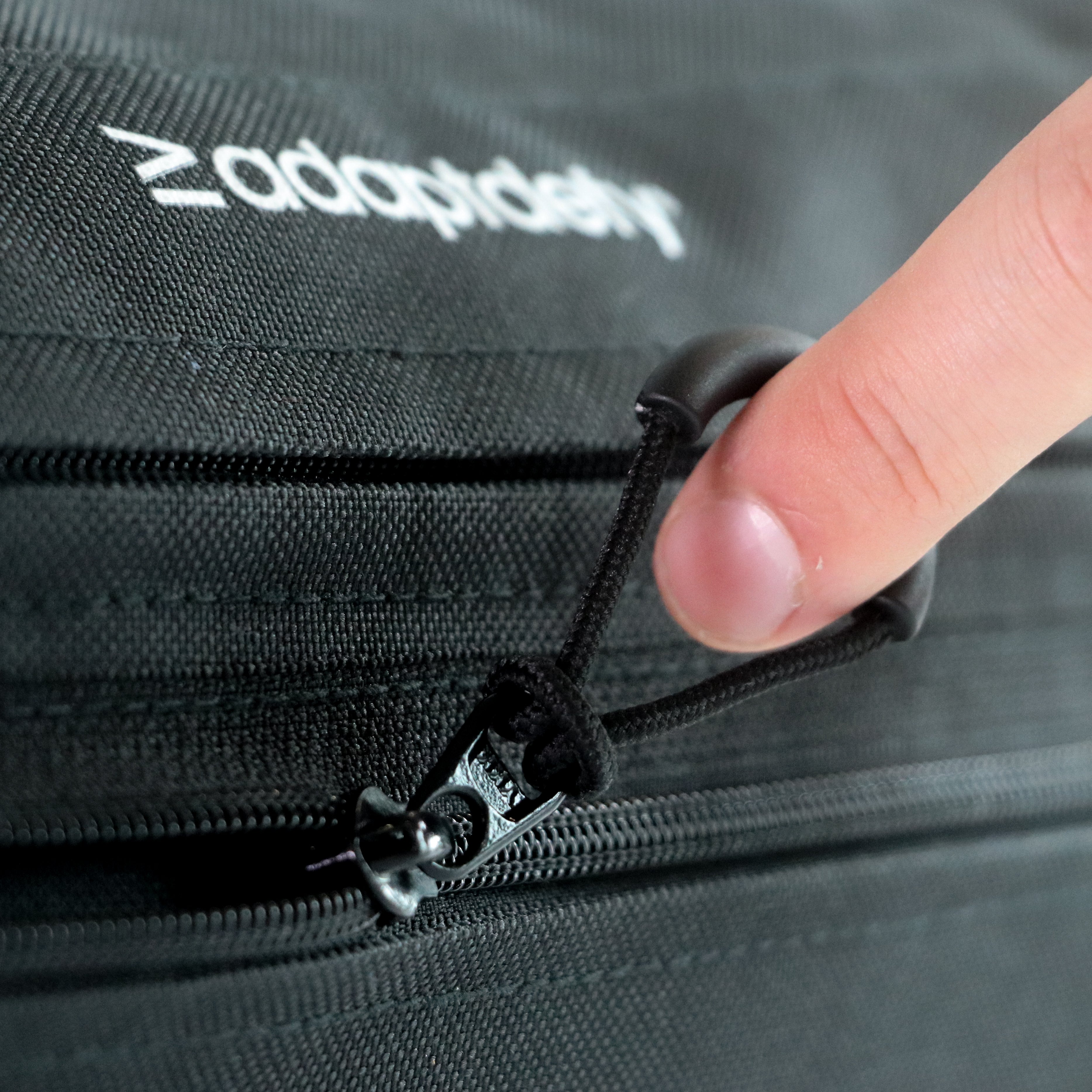 Person opening a black wheelchair bag via the zippers with 'adaptdefy' branding.