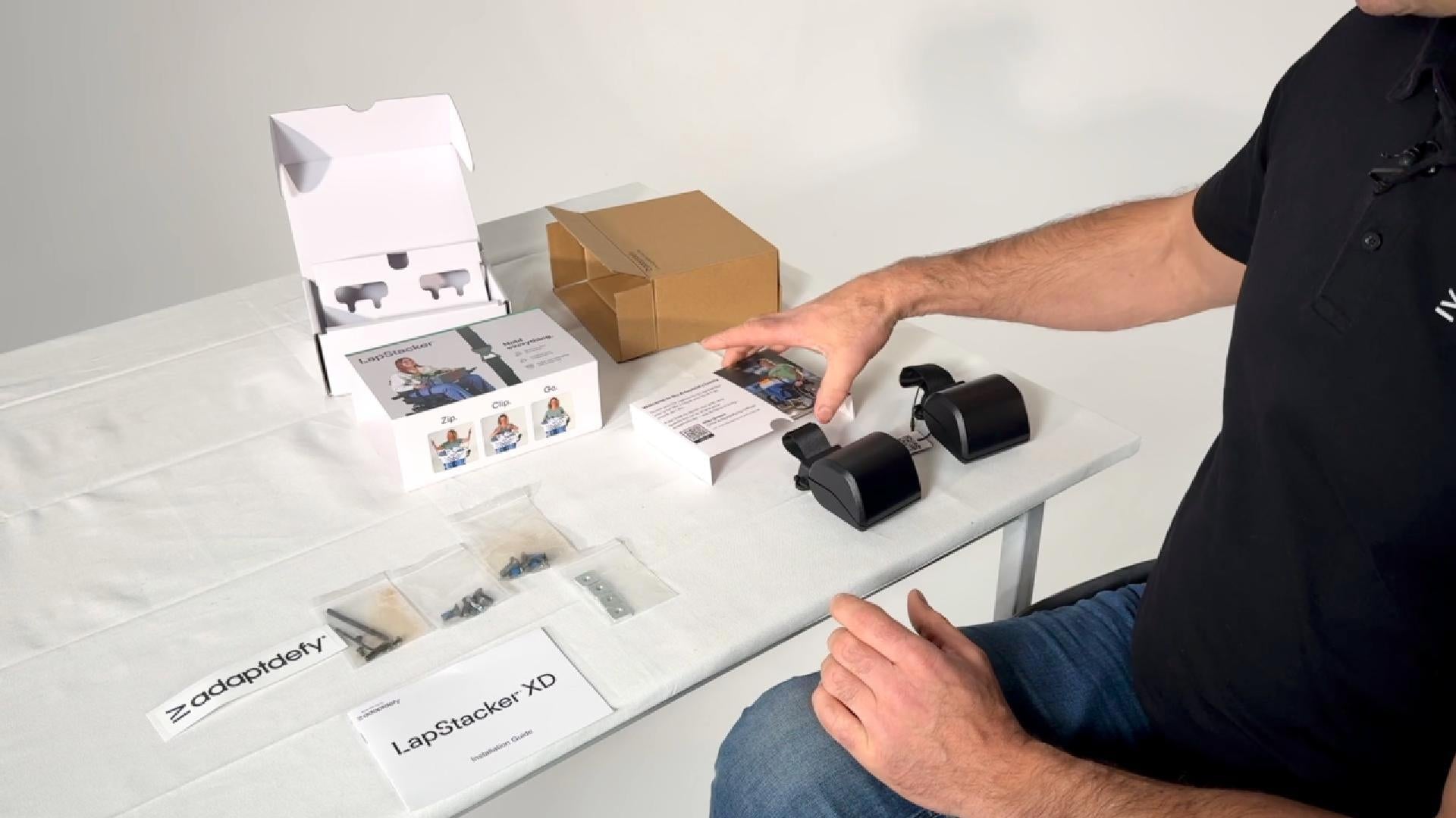 A man in a wheelchair showing what is in the box of a LapStacker XD.