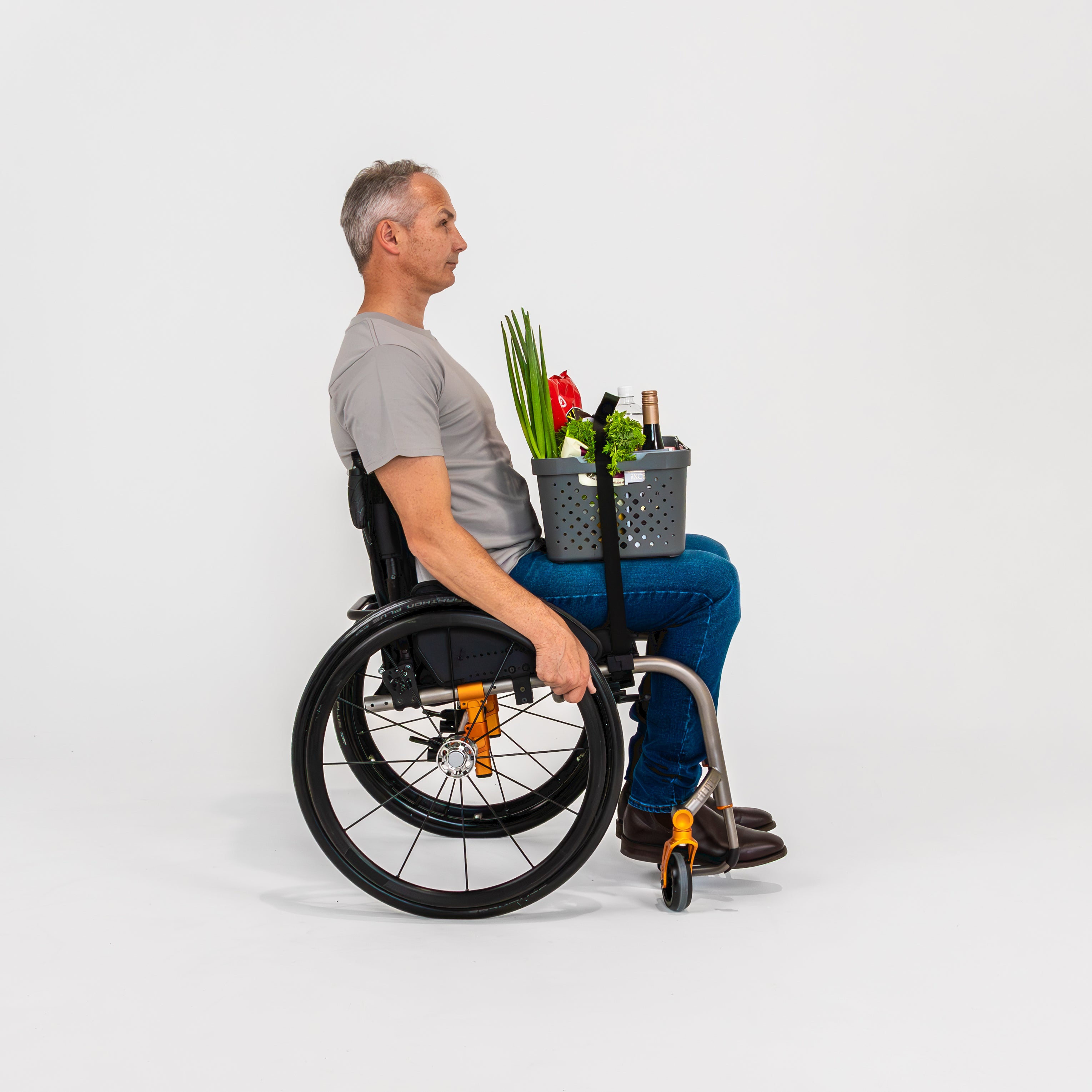 Smiling man seated in a wheelchair with a box of groceries secured to his lap using LapStacker Flex.