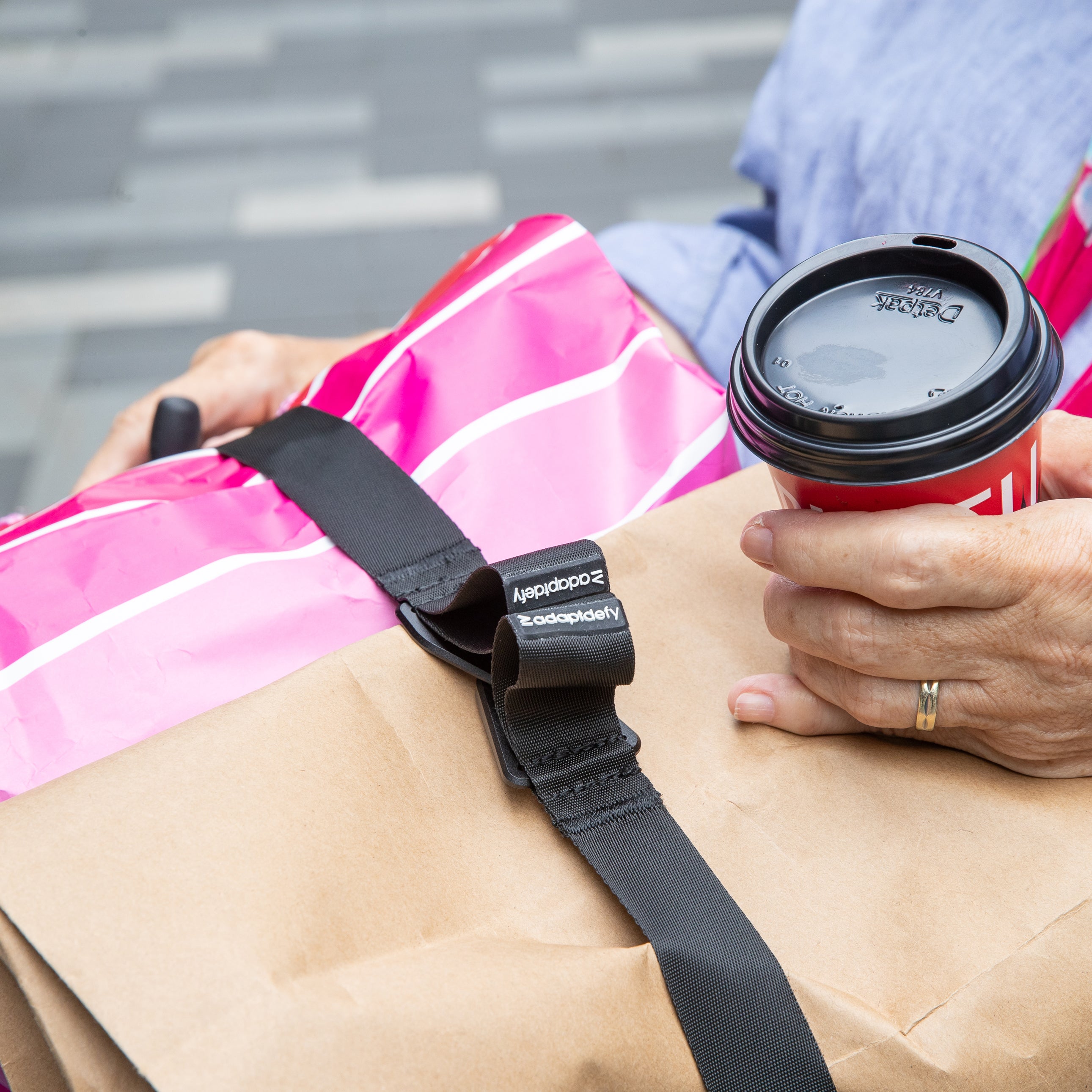 Close up of LapStacker securing shopping bags while a lady is holding a coffee in her hand