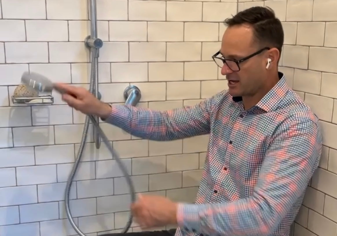 a paraplegic man sitting in an accessible shower seat demonstrating his wheelchair accessible shower setup.