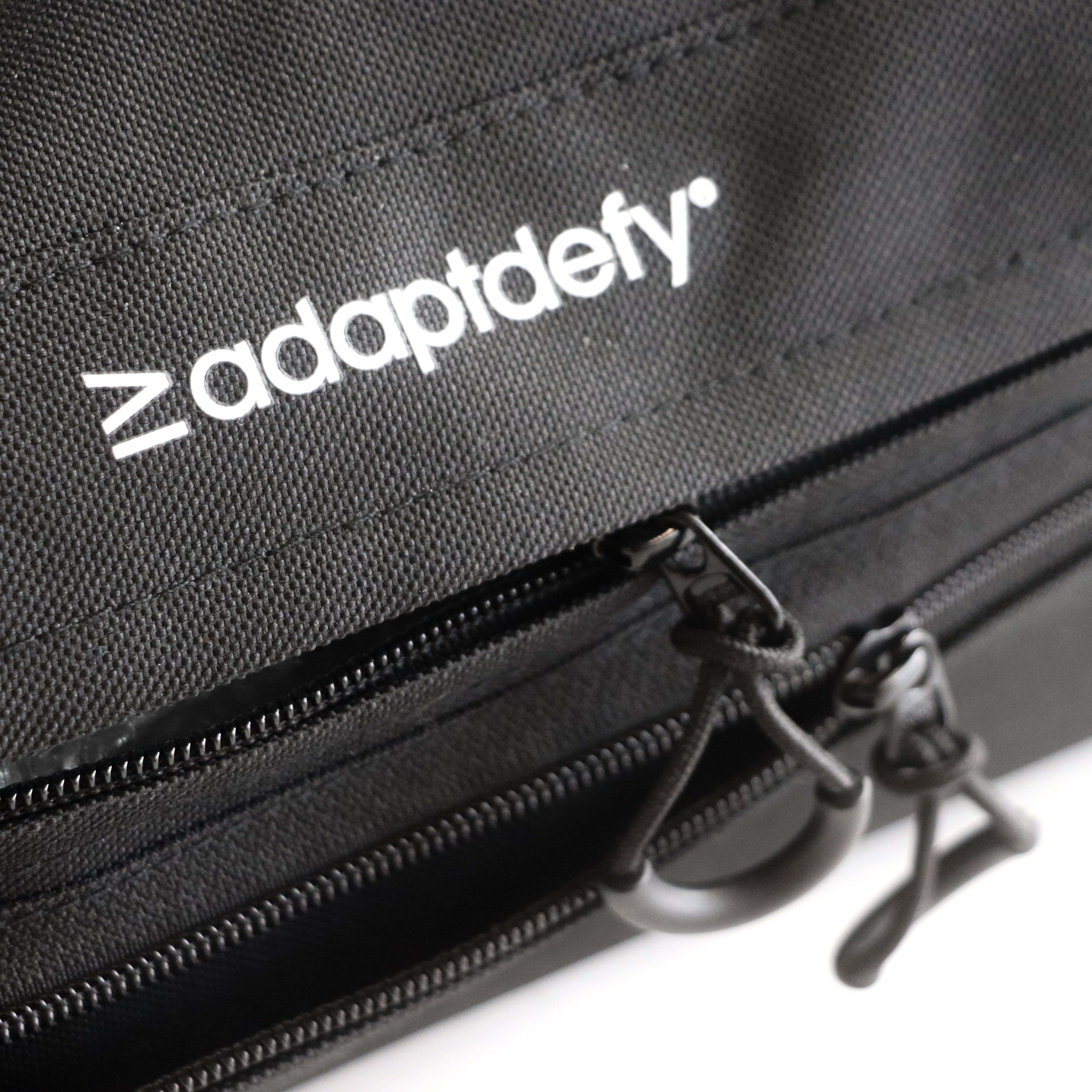 Close up of Adaptdefy branding on Defiance underseat wheelchair bag. Easy to pull zippers shown half open on both pockets. 