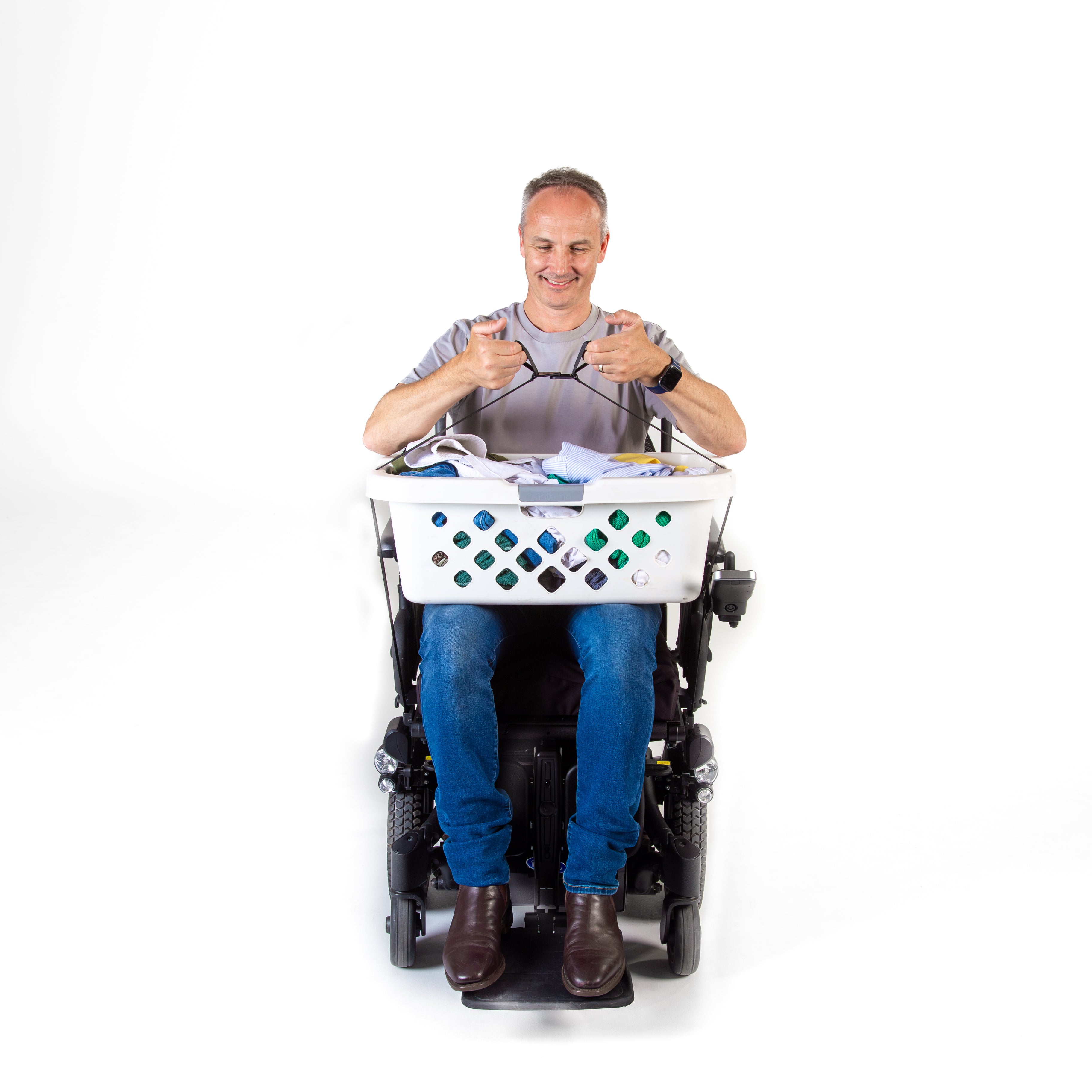 Person sitting in a power wheelchair with a laundry basket full of clothes, connecting magnetic buckles on a white background