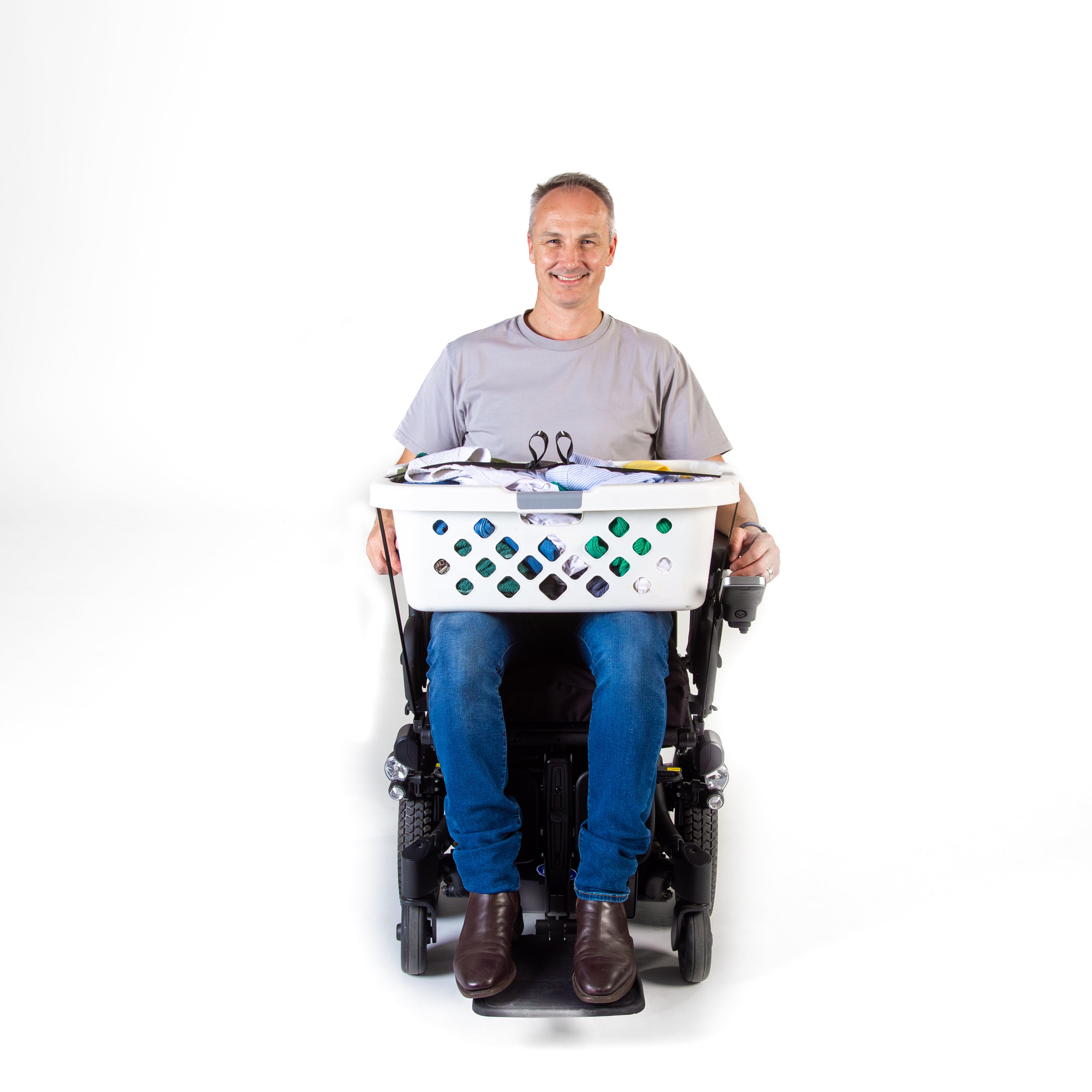 Man smiling while using a wheelchair with a laundry basket secured on a white background