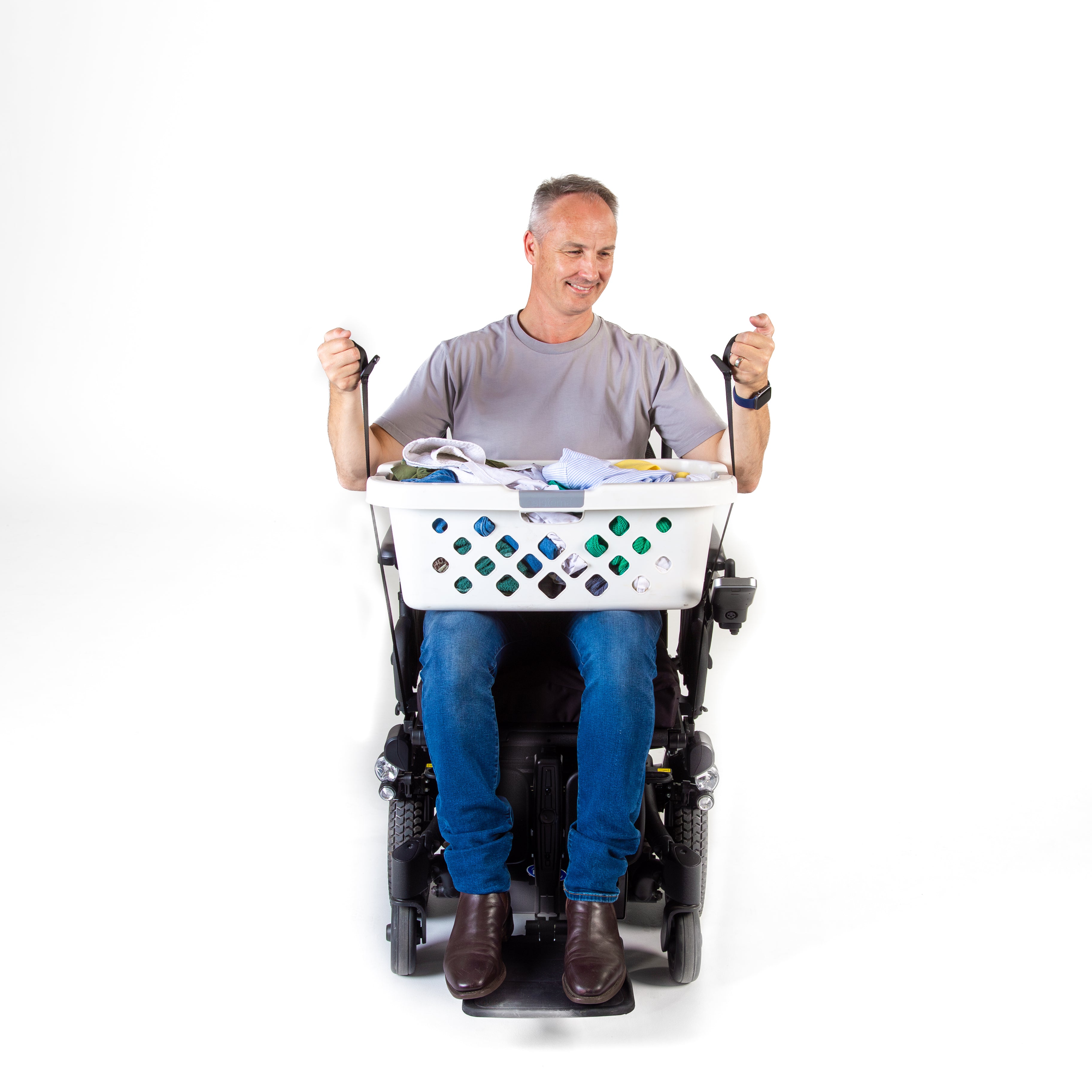 Man using a power wheelchair with a laundry basket attached, pulling up the straps on a white background
