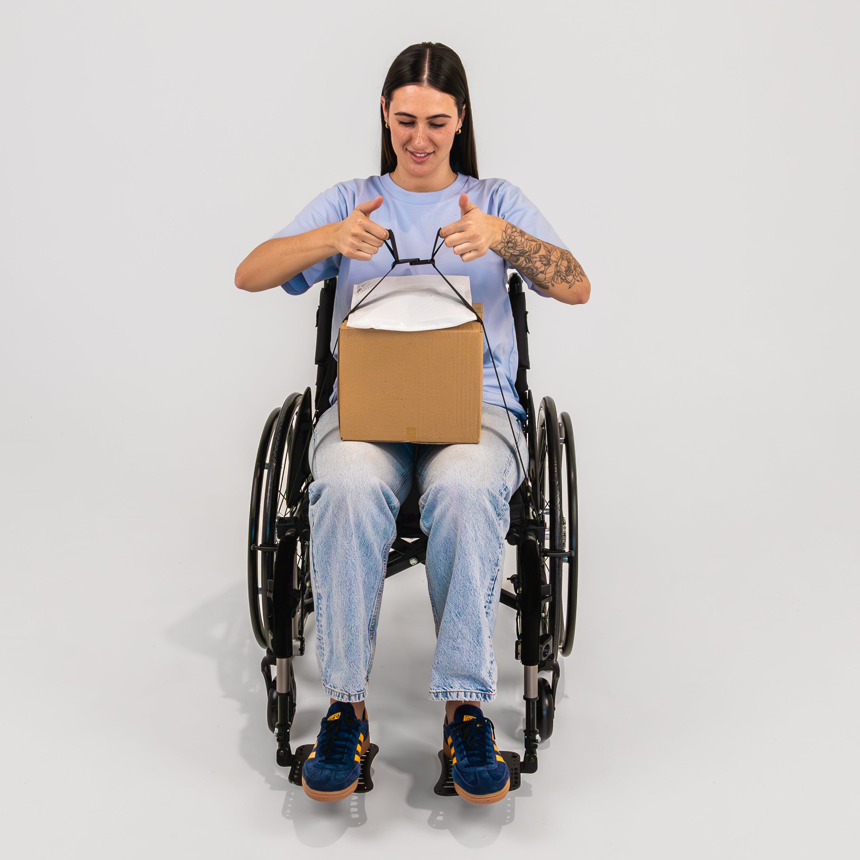Smiling women seated in a wheelchair securing a box to her lap using LapStacker Flex.