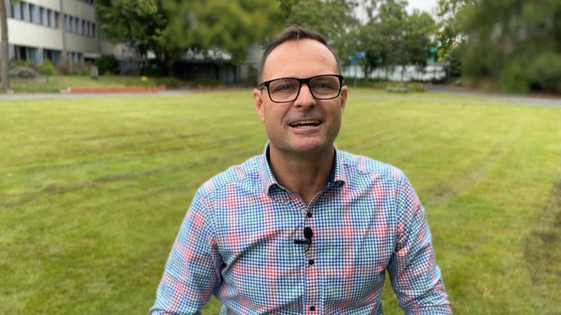 Mike in his wheelchair with bright shirt with trees in the background