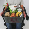 Man in a power wheelchair using LapStacker XD to strap groceries, laundry,   gifts, work items, cleaning supplies, luggage, picnic basket and boxes to his lap, before he straps a grocery basket to his lap with the LapStacker XD and drives off smiling. 